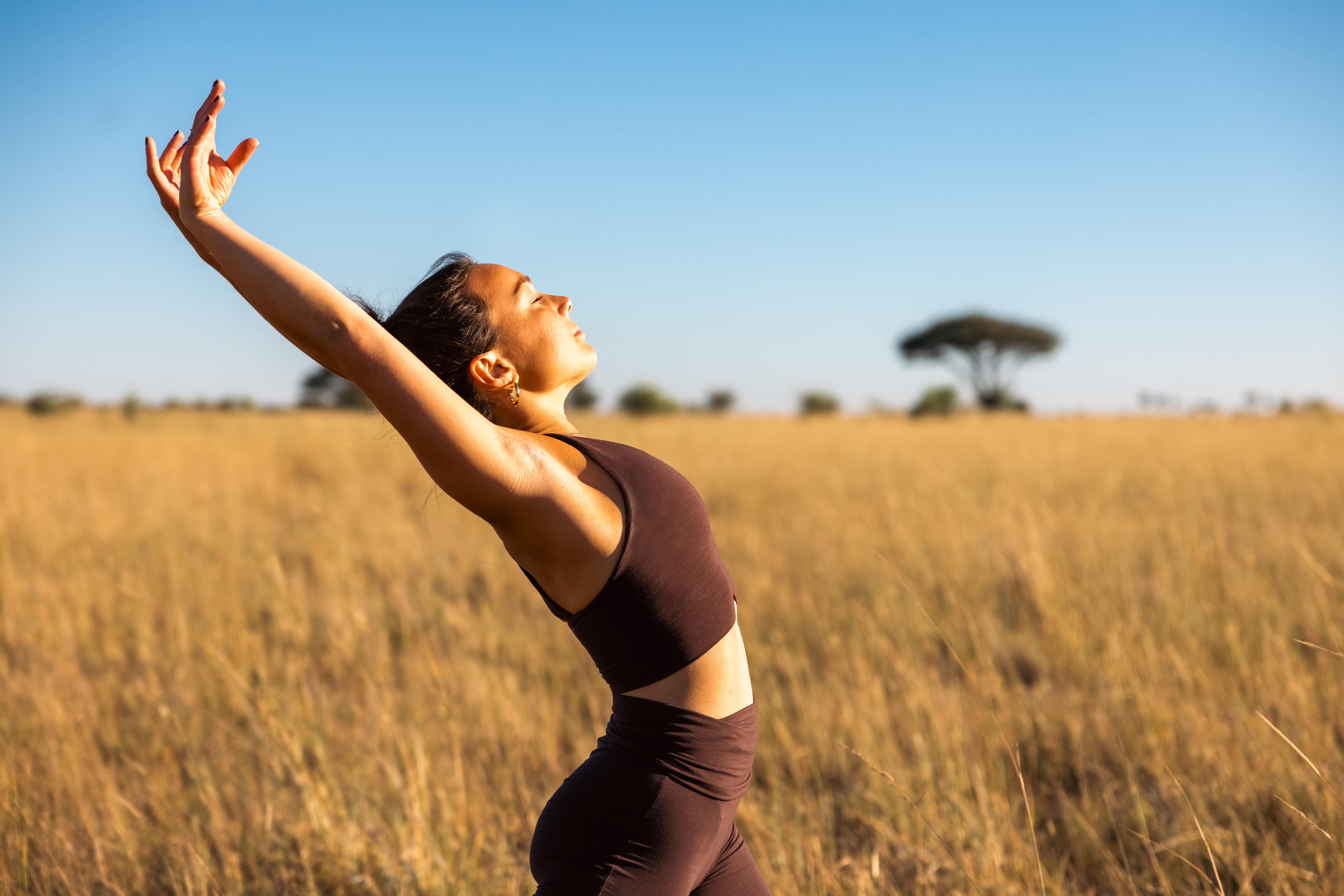 Reaching up into a sunrise yoga stretch on the savannah.